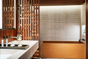 A modern bathroom with a wooden vanity, a freestanding bathtub, and a decorative wooden panel.