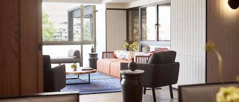 A modern living room with a sofa, chairs, a coffee table, and a vase of flowers.
