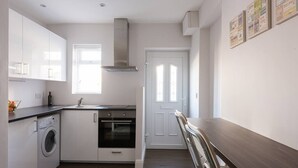 A compact kitchen with a washing machine, oven, and a window providing natural light. - Spectacular Modern Apartment (5 mins to tube) (Greater London)