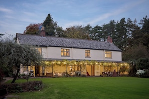 Une maison à deux étages avec une pelouse bien entretenue et un patio couvert agrémenté de guirlandes lumineuses.