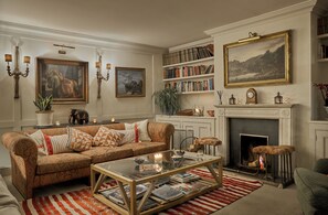 Ein gemütliches Wohnzimmer mit Kamin, Bücherregalen und einer bequemen Couch.