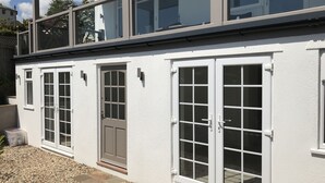 Een gebouw met twee verdiepingen, witte buitenmuren en grote ramen.