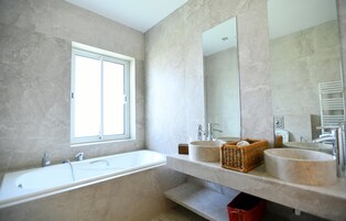 Une salle de bain moderne avec une grande baignoire, deux lavabos, une fenêtre et un grand miroir.