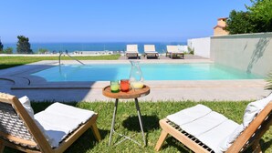 A poolside area with lounge chairs, a table with drinks, and a view of the ocean. - Villa Panorama (La Marsa)