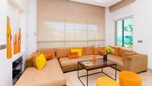 A modern living room with a sectional sofa, a coffee table, and a large window with blinds. - Villa Panorama (La Marsa)
