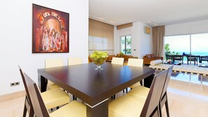 A modern dining area with a large table, comfortable chairs, and a view of the ocean. - Villa Panorama (La Marsa)