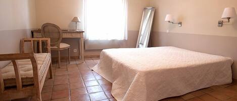 A bedroom with a bed, a desk, a chair, and a window.