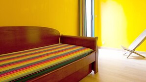 A bed with a colorful striped bedspread in a room with yellow walls and a wooden floor. - La Villa Sanary-Sur-Mer (Sanary-sur-Mer)