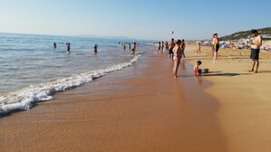 A beach with people walking along the shore and playing in the water. - Casa da Vista Rio  (Amora)