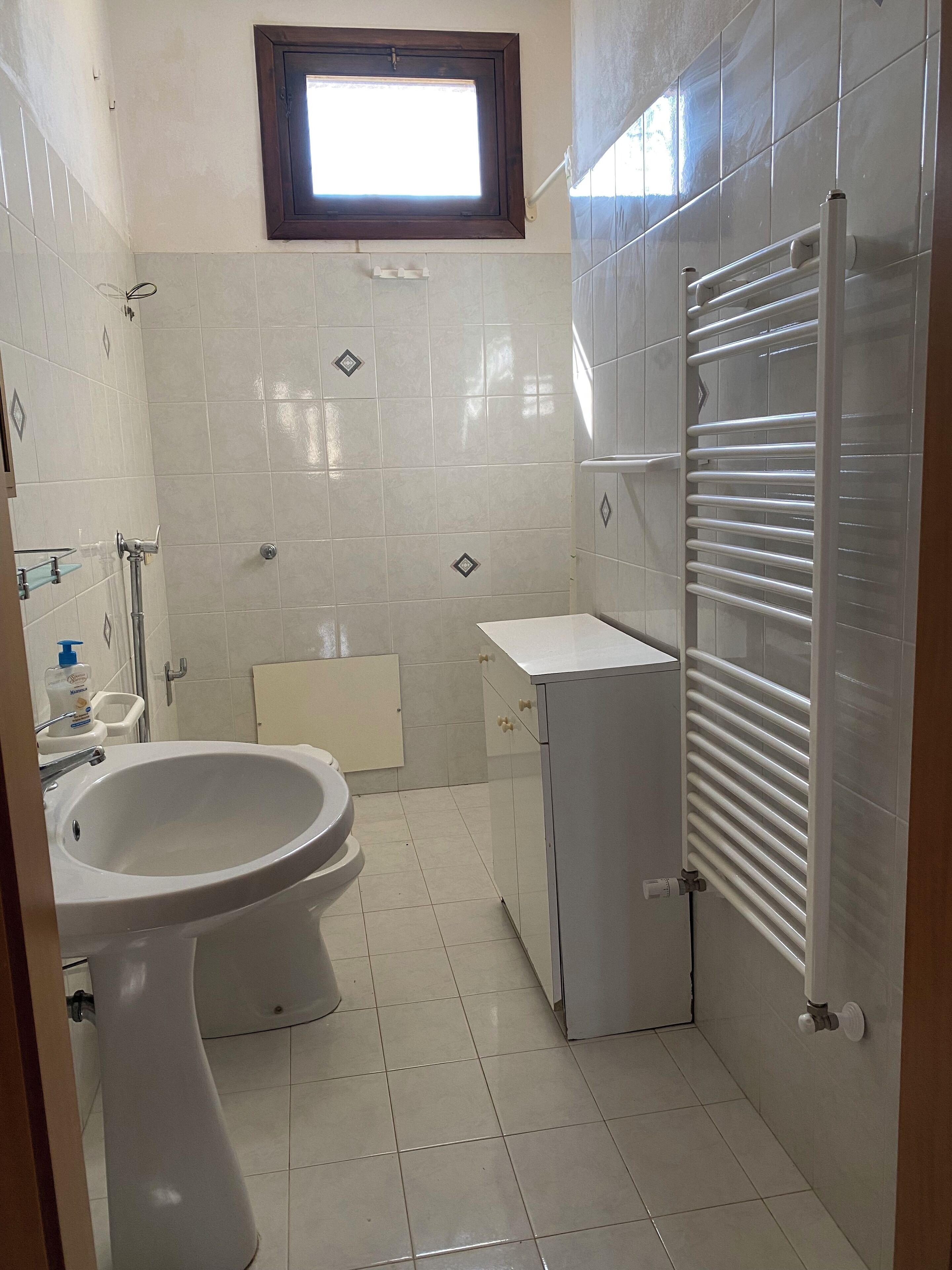 A small bathroom with a toilet, sink, and a towel rack.
