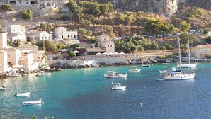 A coastal village with stone buildings, a marina with boats, and a rocky hillside in the background. - Anaroussa maisonette in Mani near all attractions (Areopoli)
