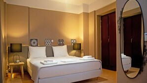 A neatly arranged hotel room with a large bed, bedside lamps, a small table, and a mirror. - Anaroussa maisonette in Mani near all attractions (Areopoli)