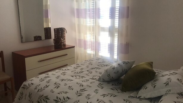 A bedroom with a bed, a dresser, a mirror, and a window with sheer curtains. - HOLIDAY HOUSE OF CORALS (Vieste)