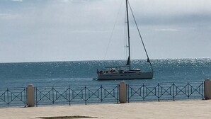 A waterfront promenade with a sailboat anchored in the distance. - HOLIDAY HOUSE OF CORALS (Vieste)