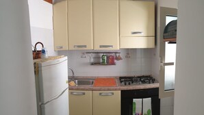 A compact kitchen with a refrigerator, sink, stove, and cabinets. - HOLIDAY HOUSE OF CORALS (Vieste)