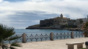 A coastal town with a prominent building featuring a bell tower, situated on a rocky outcrop with a clear view of the sea. - HOLIDAY HOUSE OF CORALS (Vieste)