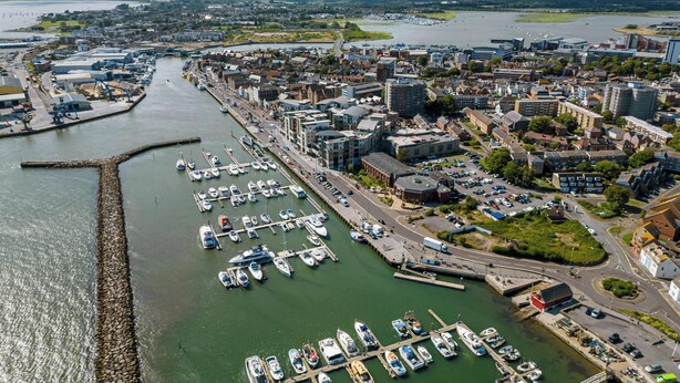 An aerial view of a marina with boats docked, surrounded by urban buildings and a river. - Dolphin Cottage  - Short walk to Poole Quay (Poole)