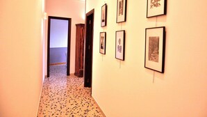 A hallway with framed pictures on the walls and a door at the end. - CASA ROSETTA Palermo Mondello (Palermo)