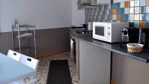 A compact kitchen with a microwave, stove, and a tiled backsplash. - CASA ROSETTA Palermo Mondello (Palermo)