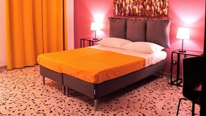 A hotel room with a bed, two bedside tables with lamps, a wall-mounted air conditioner, and a large abstract painting. - CASA ROSETTA Palermo Mondello (Palermo)