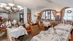 Un restaurante con varias mesas, sillas de madera y una araña.