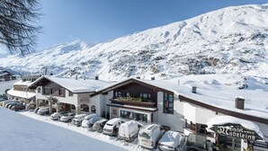 Un complejo turístico en la montaña, cubierto de nieve, con varios edificios, incluyendo un restaurante y un hotel.