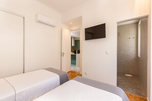 A hotel room with two beds, a TV, and a shower.