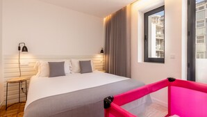 Hotellihuone, jossa on sänky, yöpöytävalaisimet, ikkuna ja näkymä ulos.
