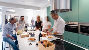 Moderni keittiö, jossa on turkoosinsiniset kaapit, ruostumattomasta teräksestä valmistettu liesituuletin ja sisäänrakennettu uuni.