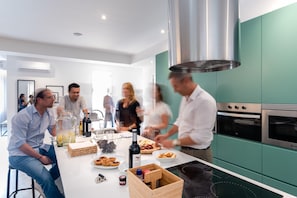Una cucina moderna con mobili color petrolio, una cappa in acciaio inossidabile e un forno integrato.
