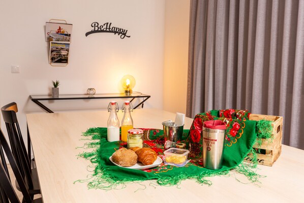 A breakfast setup with croissants, milk, and a thermos on a table with a green cloth.