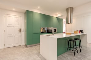Una cucina moderna con mobili verdi, una cappa in acciaio inossidabile e un'isola bianca con sgabelli da bar.
