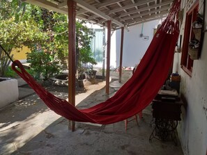 A hammock under a wooden pergola, a sewing machine, and potted plants in a courtyard. - COMFORTABLE INDEPENDENT ROOM WITH AIR CONDITIONING (Cartagena)