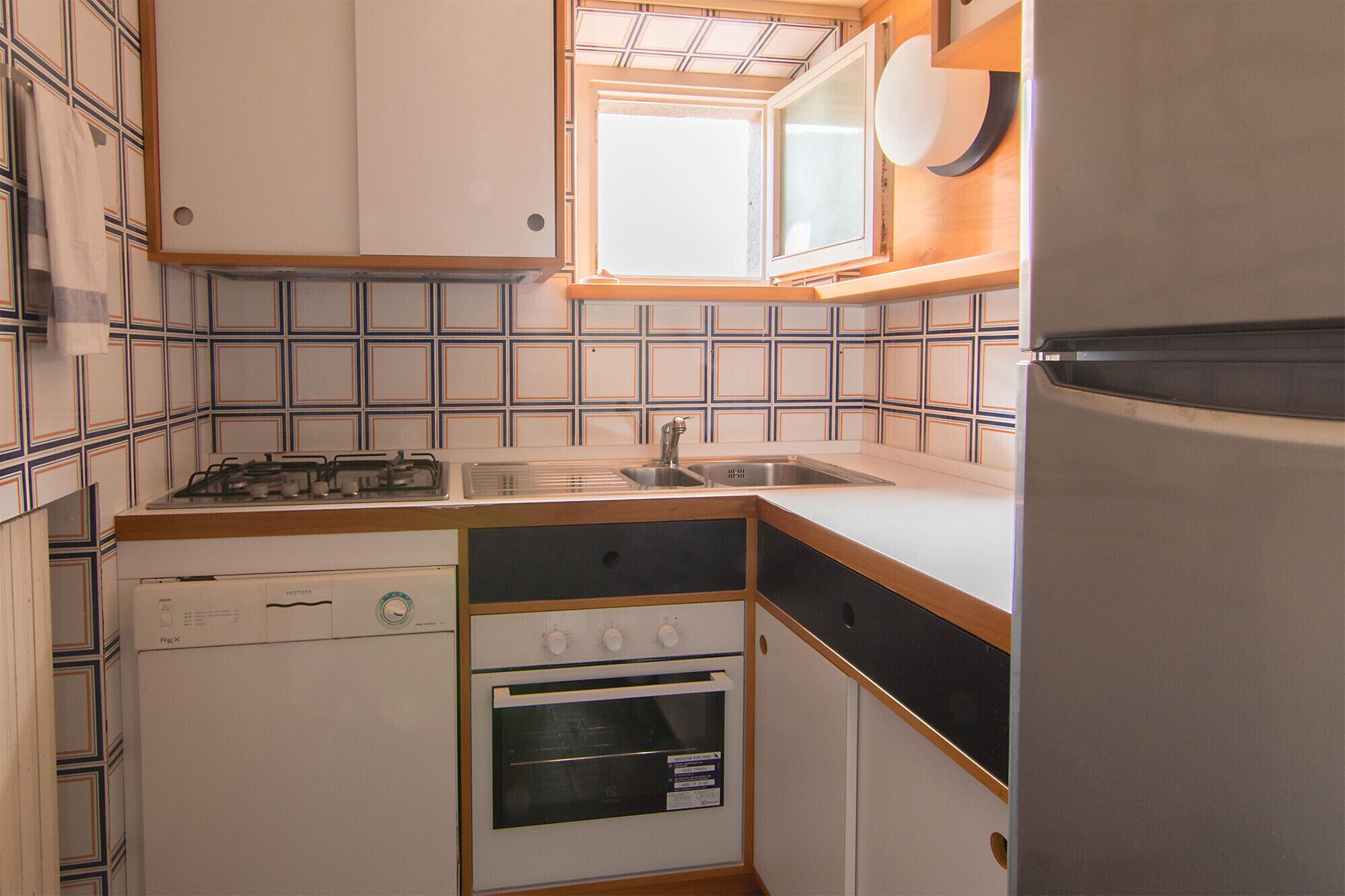 Een kleine keuken met een gasfornuis, spoelbak en een ingebouwde oven.