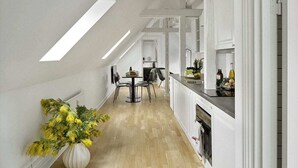 Une cuisine moderne avec des meubles blancs, un plancher en bois et un coin repas comprenant des chaises et une table.