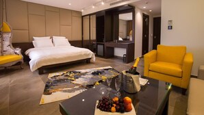 A modern hotel room with a large bed, a desk, a yellow armchair, and a fruit bowl on the desk. - The Opera Hotel (Kfar Yassine)