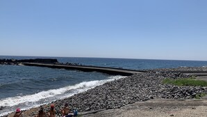 A rocky beach with waves crashing onto the shore, a clear sky, and a distant view of the ocean. - Superb vacation home (Torre archirafi)