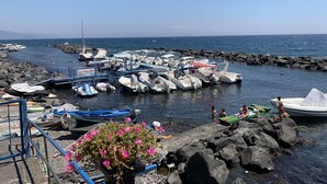 A marina with various boats docked, rocky shore, and a clear sky. - Superb vacation home (Torre archirafi)