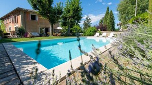 Una piscina con cubierta de madera, rodeada de árboles y una casa.