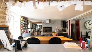 Una cocina acogedora con una mesa y sillas de madera, un reloj en la pared y diversos electrodomésticos.