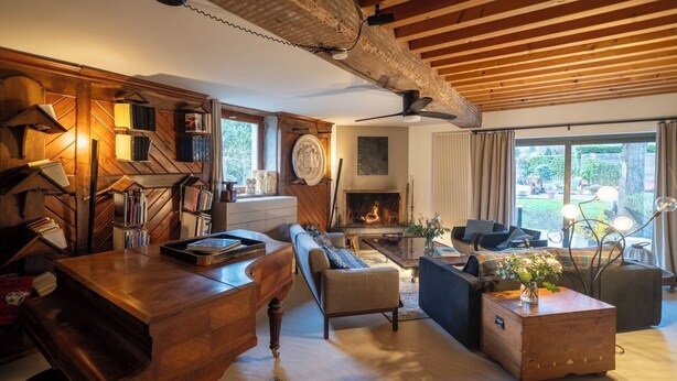 Una sala acogedora con chimenea, estanterías de madera, un piano y asientos cómodos.