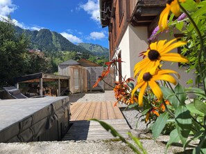 A wooden deck with a lounge chair, a small wooden structure, and a mountain backdrop. - 4 Bedroom all ensuite - Portes du Soleil Morzine, All year round Fun Domaine (Saint-Jean-d'Aulps)