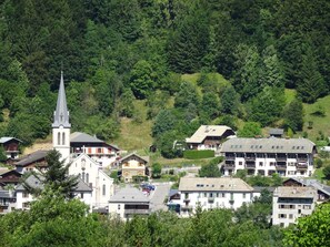 Une ville avec une église, des immeubles d’habitation et une colline couverte d’une forêt dense.