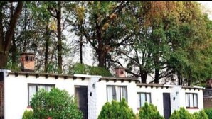 A two-story white building with a flat roof, surrounded by well-maintained hedges and trees. - Club Santa Maria (Cuernavaca)