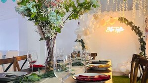 A dining table set with plates, glasses, and cutlery, decorated with a floral centerpiece and hanging paper lanterns. - Club Santa Maria (Cuernavaca)