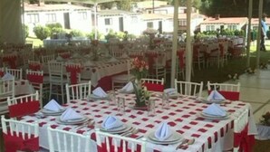 An outdoor tented event space with round tables set for dining, white chairs, and red sashes. - Club Santa Maria (Cuernavaca)