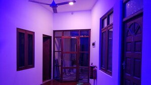 A hallway with wooden flooring, a ceiling fan, and a fire extinguisher. - Alkina Lodge (Fulidhoo)