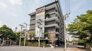 A multi-story building with a prominent sign, balconies, and a website URL. - Nidhra Residence (Lam Luk Ka)