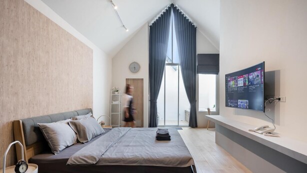 A modern bedroom with a bed, a TV, and a desk area. - Nidhra Residence (Lam Luk Ka)