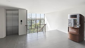 A hotel room with a large window, a water dispenser, and an elevator. - Nidhra Residence (Lam Luk Ka)